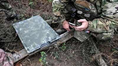 a-soldier-uses-a-smartphone-to-check-signal-quality-while-setting-up-a-starlink-satellite-communicat.jpeg